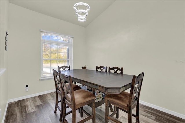 dining room featuring a chandelier, dark hardwood / wood-style floors, and vaulted ceiling