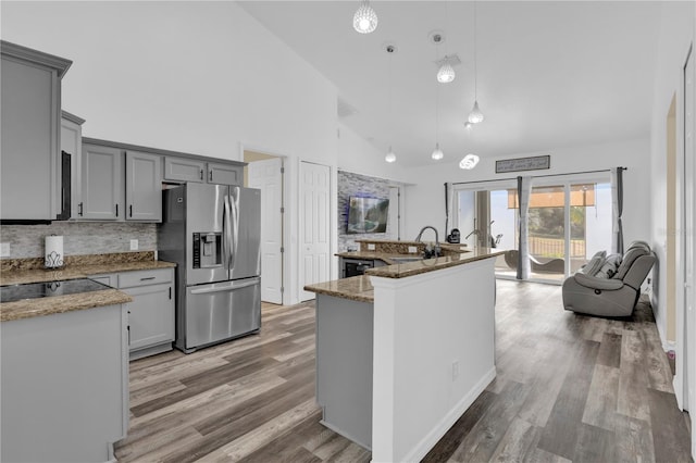 kitchen with hanging light fixtures, stainless steel fridge with ice dispenser, high vaulted ceiling, wood-type flooring, and gray cabinets