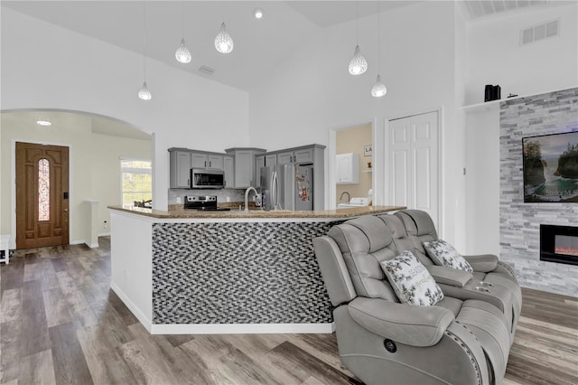 living room featuring a tile fireplace, hardwood / wood-style floors, high vaulted ceiling, and sink