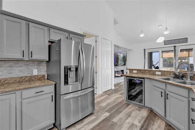 kitchen with sink, hanging light fixtures, wine cooler, stainless steel fridge, and lofted ceiling