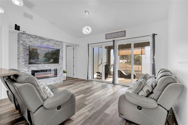 living room featuring light wood-type flooring, lofted ceiling, and a fireplace