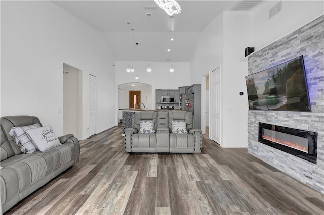 living room with dark hardwood / wood-style flooring, a fireplace, high vaulted ceiling, and sink