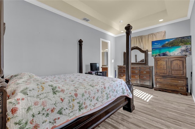 bedroom with a tray ceiling, crown molding, and light wood-type flooring