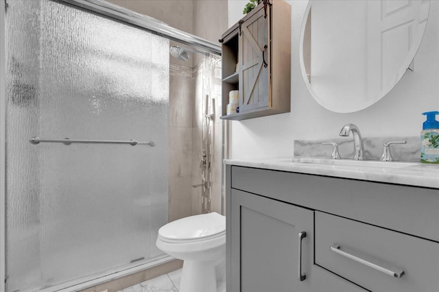 bathroom with vanity, toilet, and a shower with door