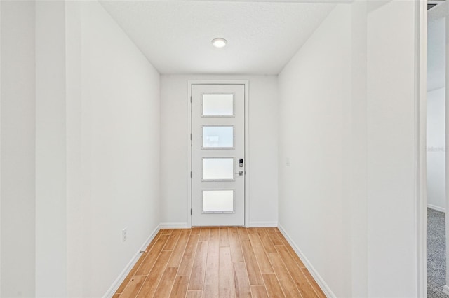 doorway to outside with a textured ceiling and wood-type flooring