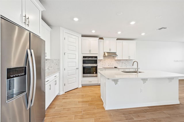 kitchen with sink, stainless steel appliances, white cabinets, and a center island with sink