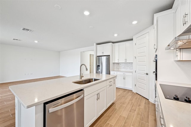 kitchen with stainless steel appliances, an island with sink, decorative backsplash, white cabinetry, and sink