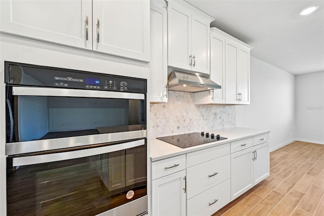 kitchen with light hardwood / wood-style floors, black electric stovetop, backsplash, double oven, and white cabinets