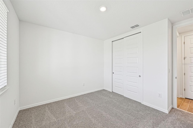 unfurnished bedroom featuring a closet, multiple windows, and light colored carpet