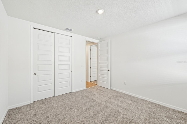 unfurnished bedroom featuring a textured ceiling, a closet, and carpet