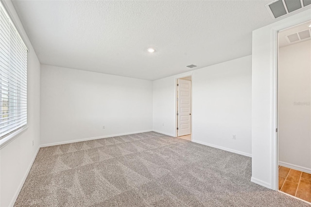 carpeted spare room featuring a textured ceiling