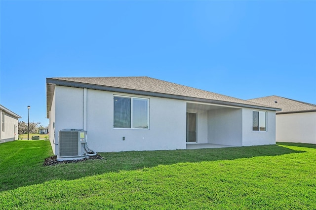 rear view of house with cooling unit and a lawn