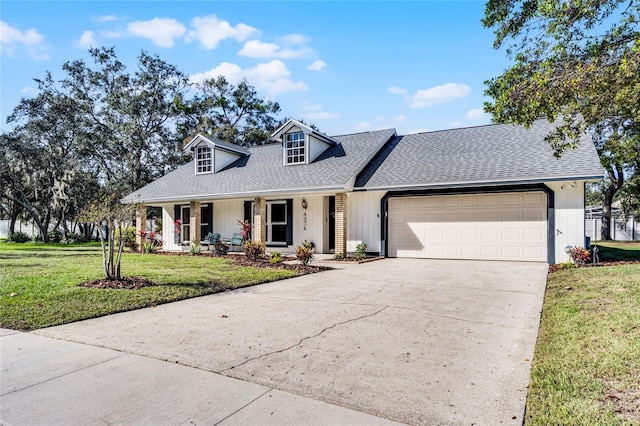 cape cod home with a front yard, driveway, covered porch, a shingled roof, and a garage