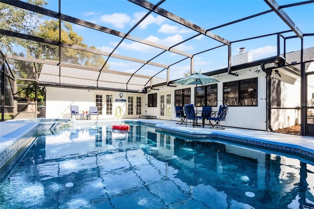 view of pool with a lanai, a patio, an in ground hot tub, and french doors