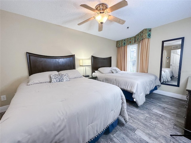 bedroom with hardwood / wood-style floors, ceiling fan, and a textured ceiling