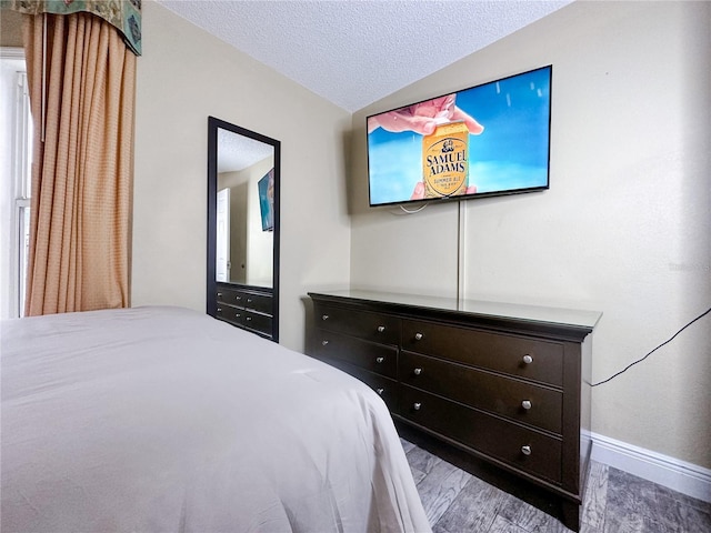 bedroom featuring a textured ceiling, hardwood / wood-style floors, and vaulted ceiling