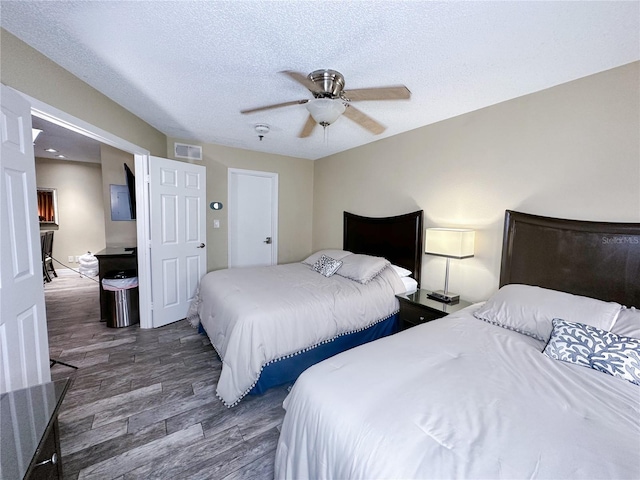 bedroom featuring a textured ceiling, ceiling fan, and dark hardwood / wood-style floors