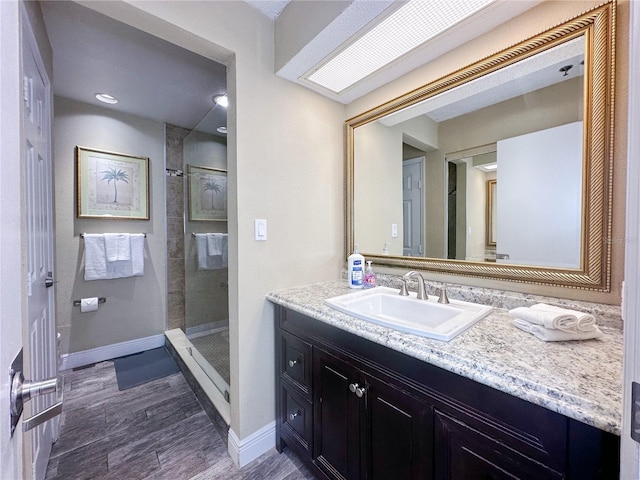 bathroom with hardwood / wood-style floors, vanity, and a tile shower