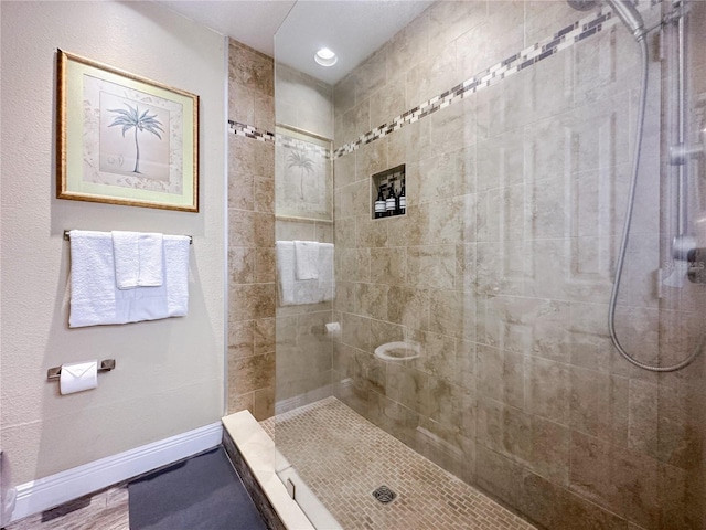 bathroom with a tile shower and wood-type flooring