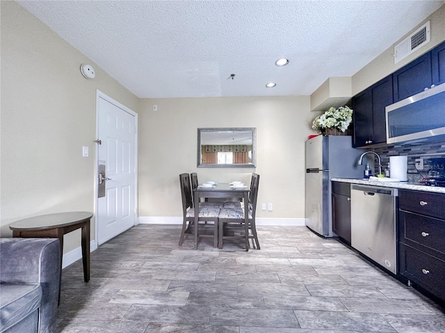 kitchen featuring dishwasher, a textured ceiling, tasteful backsplash, and sink