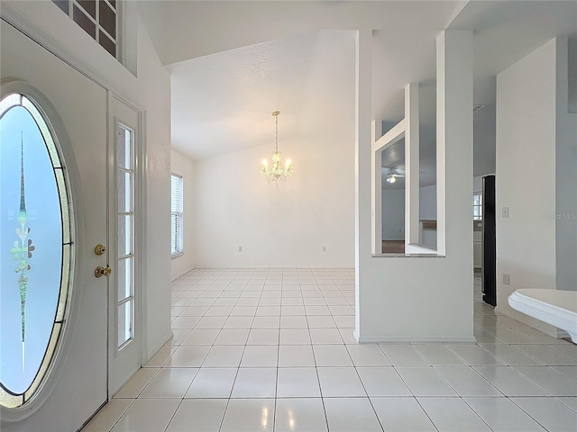 foyer featuring light tile patterned flooring, a chandelier, and vaulted ceiling