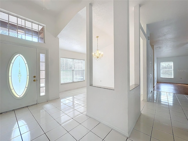 tiled foyer with a chandelier and a textured ceiling