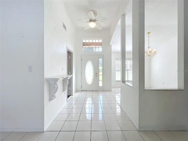 foyer with ceiling fan with notable chandelier and light tile patterned floors