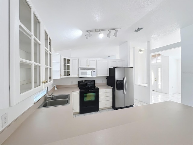 kitchen with black electric range oven, sink, stainless steel fridge, white cabinets, and light tile patterned floors