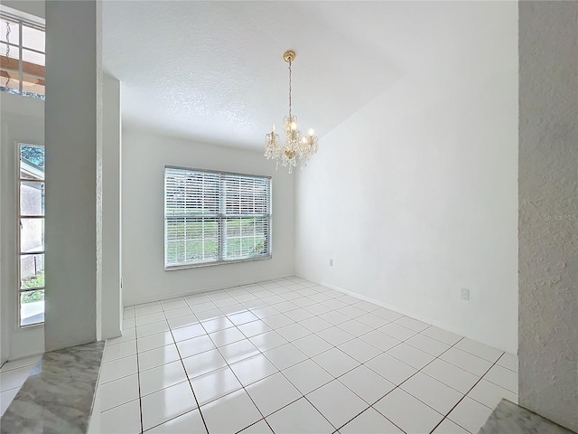 unfurnished room with light tile patterned flooring, a chandelier, and a wealth of natural light