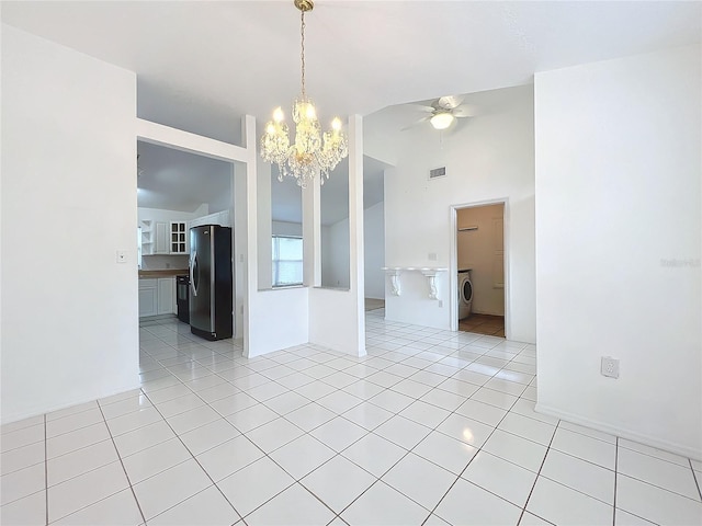 tiled spare room featuring washer / dryer, ceiling fan with notable chandelier, and lofted ceiling