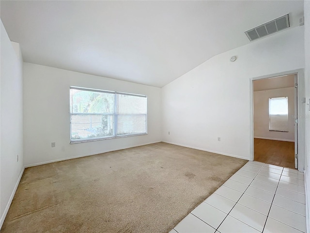 spare room featuring vaulted ceiling and light colored carpet