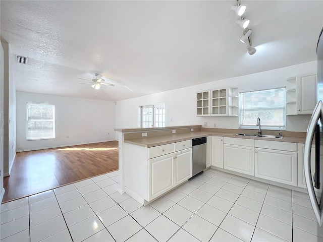 kitchen with sink, light tile patterned floors, appliances with stainless steel finishes, kitchen peninsula, and white cabinets