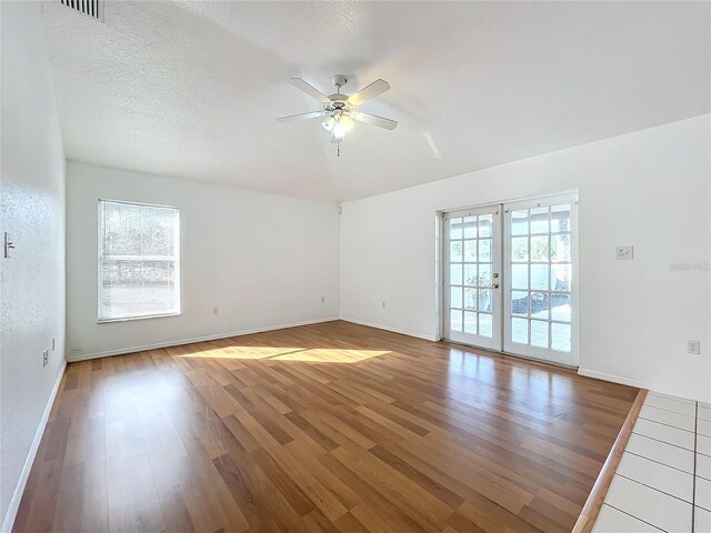 empty room with ceiling fan, hardwood / wood-style flooring, french doors, and a textured ceiling