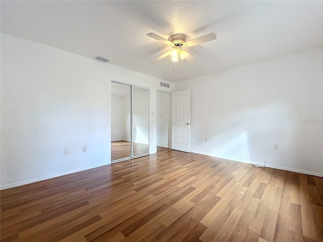 unfurnished bedroom with ceiling fan, hardwood / wood-style floors, a closet, and a textured ceiling