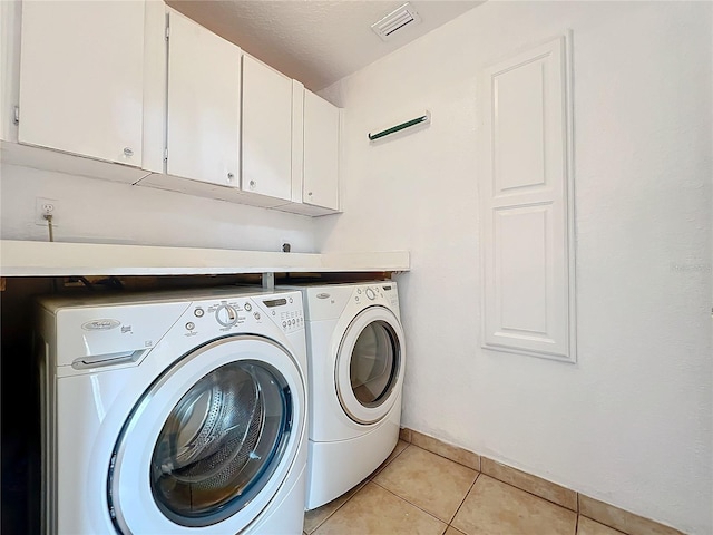 laundry area featuring cabinets, light tile patterned floors, and washer and clothes dryer