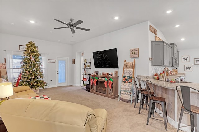 living room featuring ceiling fan, light colored carpet, and sink