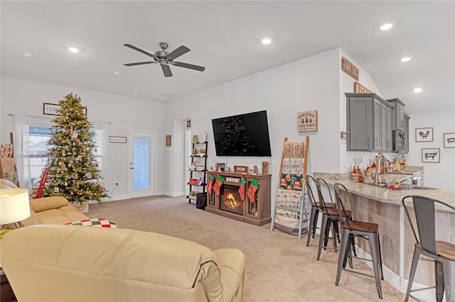 carpeted living room featuring ceiling fan and sink