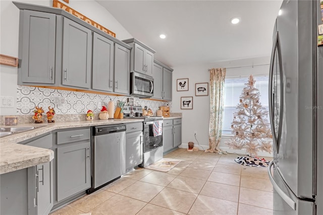 kitchen with stainless steel appliances, gray cabinetry, and light tile patterned flooring