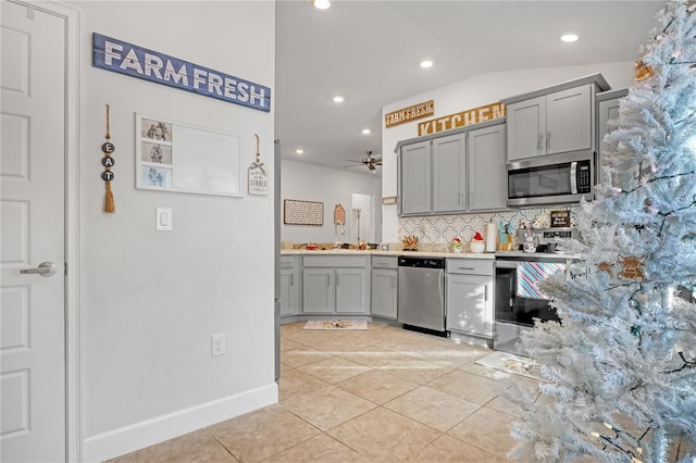 kitchen featuring ceiling fan, stainless steel appliances, backsplash, vaulted ceiling, and light tile patterned flooring