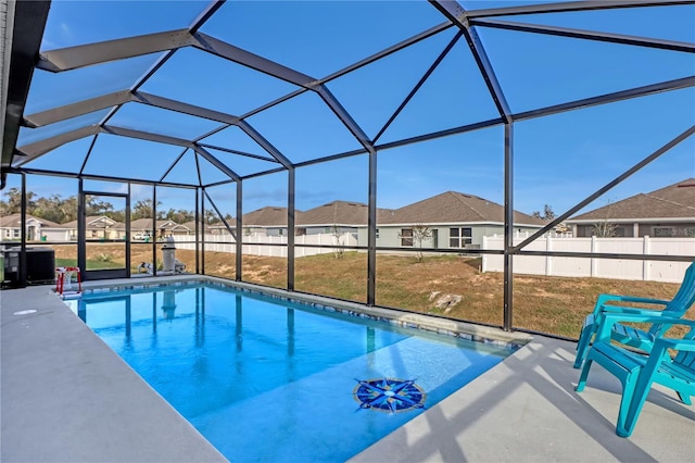 view of swimming pool featuring a lawn, glass enclosure, and a patio area