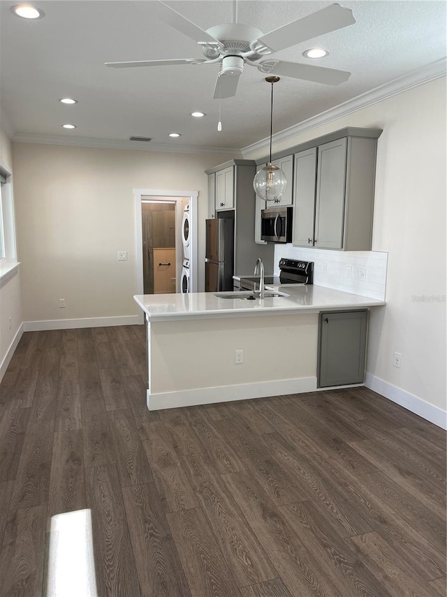 kitchen with kitchen peninsula, appliances with stainless steel finishes, dark hardwood / wood-style flooring, stacked washer and clothes dryer, and gray cabinets