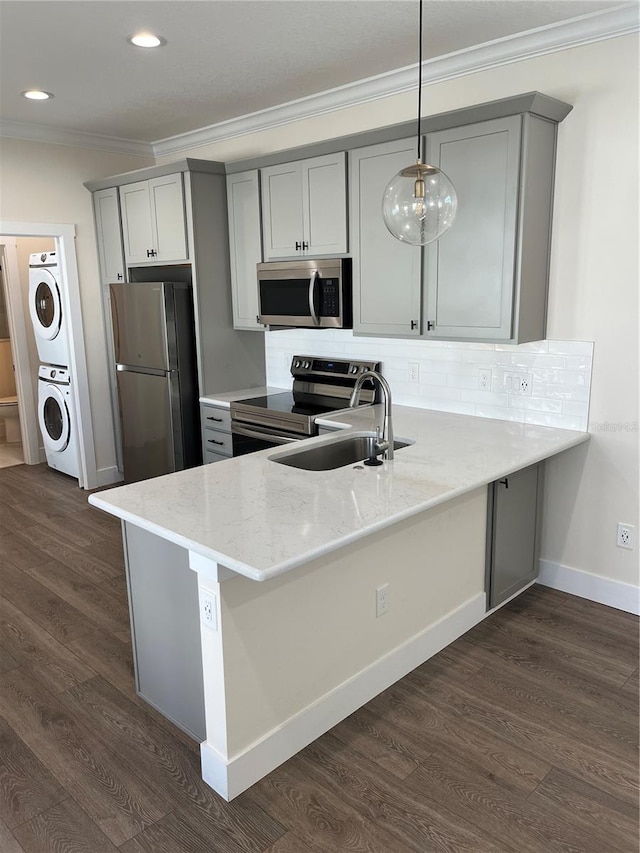 kitchen with stacked washer / dryer, hanging light fixtures, dark hardwood / wood-style floors, and appliances with stainless steel finishes