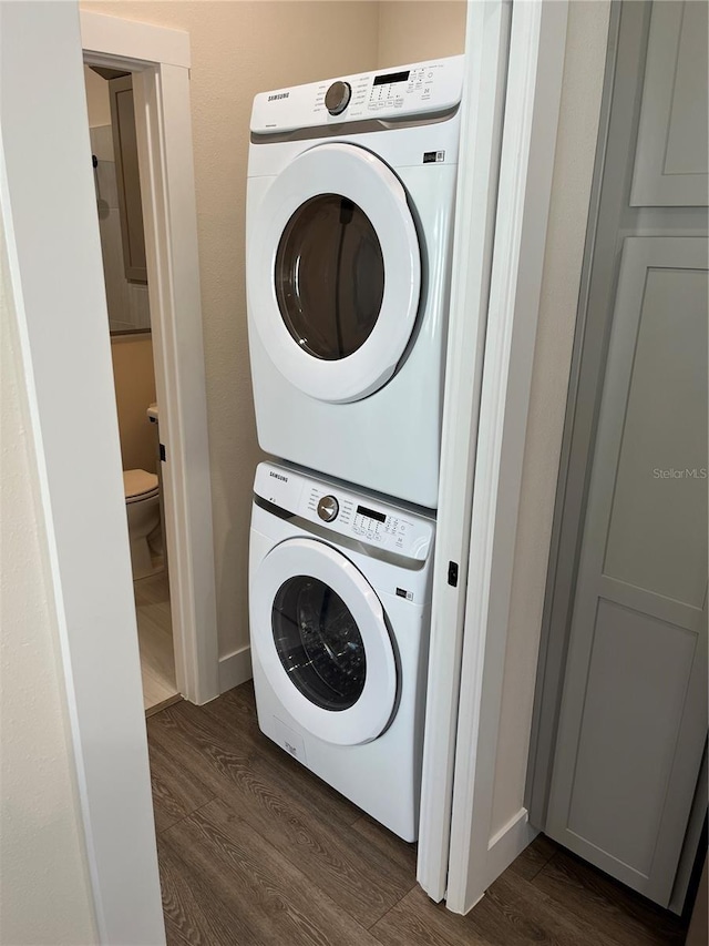 laundry area featuring stacked washing maching and dryer and dark hardwood / wood-style floors