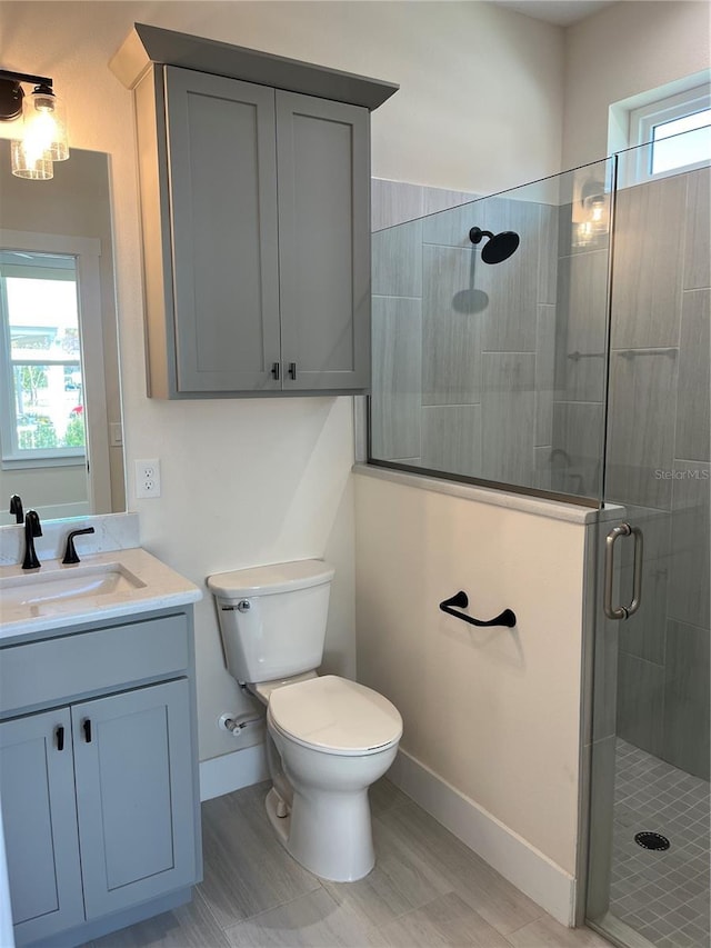 bathroom featuring plenty of natural light, vanity, a shower with shower door, and toilet