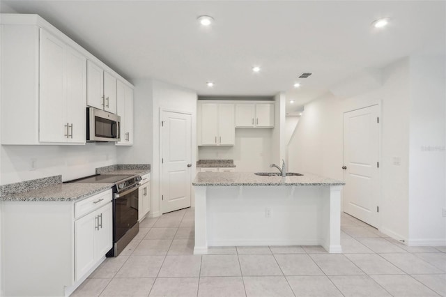 kitchen featuring white cabinets, stainless steel appliances, light stone countertops, and a center island with sink