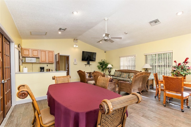 dining space with lofted ceiling, ceiling fan, light hardwood / wood-style floors, and a textured ceiling