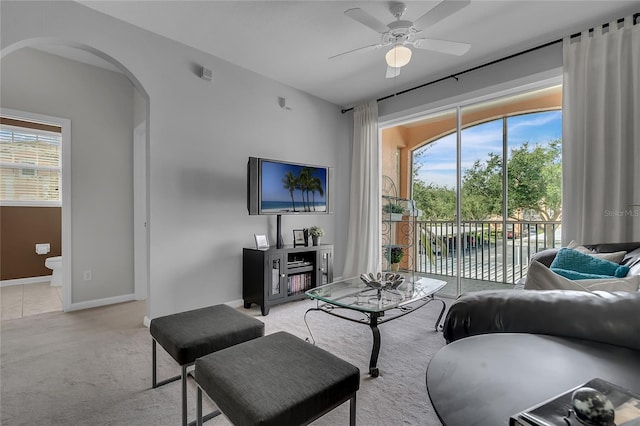 living room featuring light colored carpet, ceiling fan, and a healthy amount of sunlight