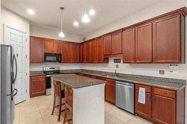 kitchen featuring appliances with stainless steel finishes, sink, decorative light fixtures, a kitchen island, and light tile patterned flooring