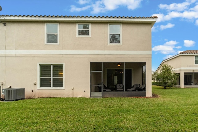 rear view of property with a sunroom, cooling unit, and a lawn