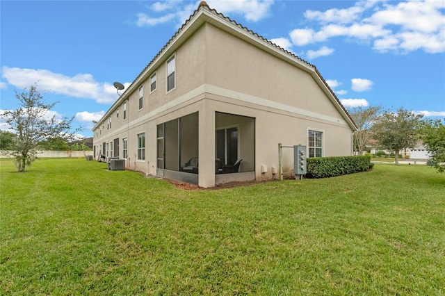 back of property with a yard, cooling unit, and a sunroom